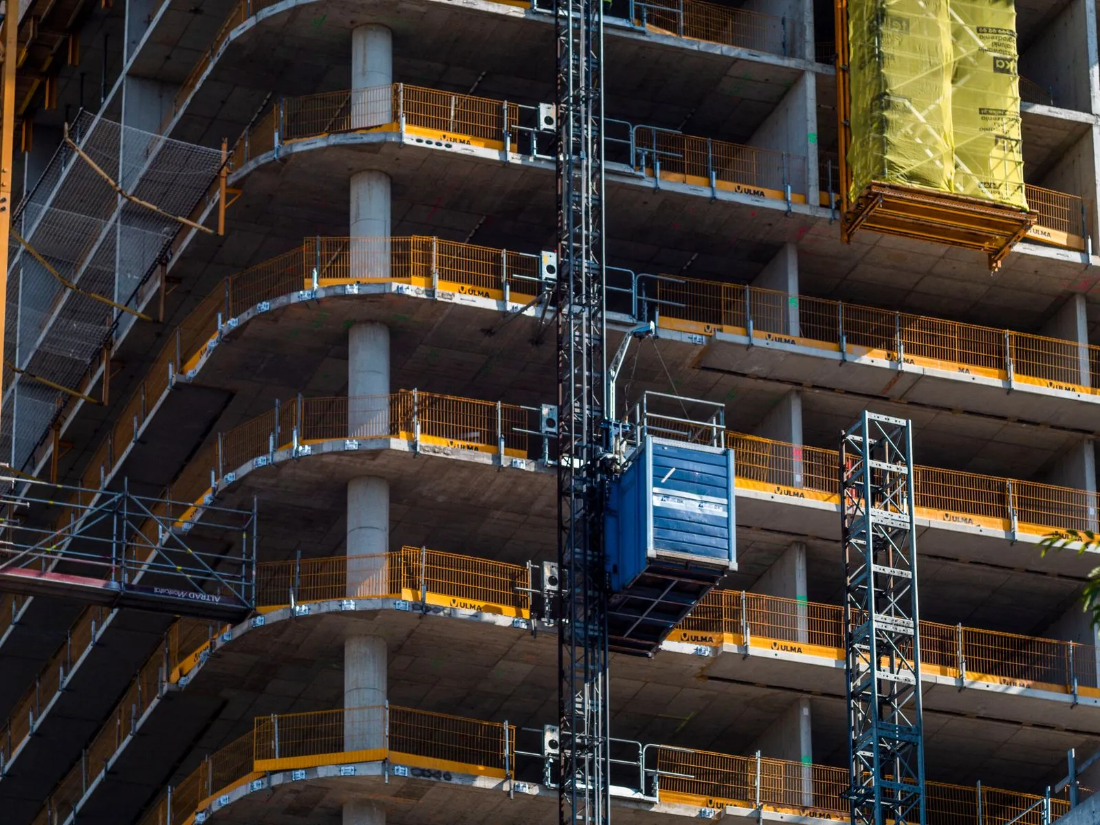 A high rise under construction with a crane and scaffolding